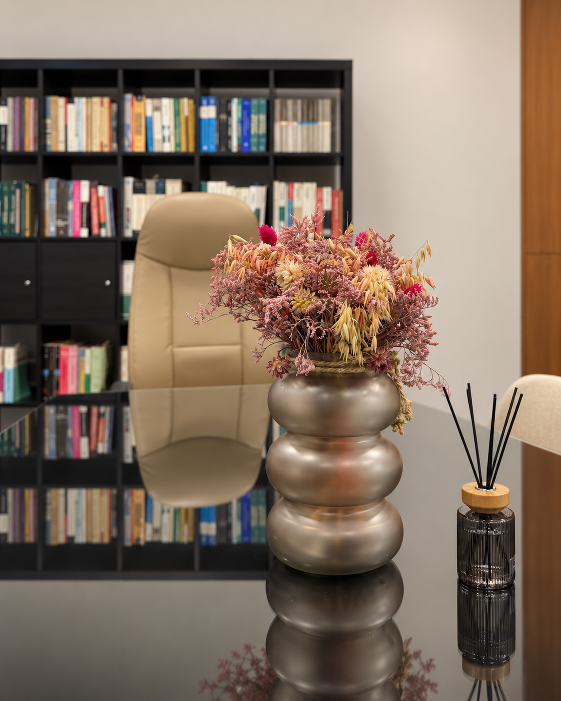 Pormenor da mesa do escritório com arranjo floral e biblioteca ao fundo